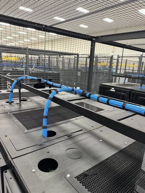 Overhead view of a data center cage with cable tray runs